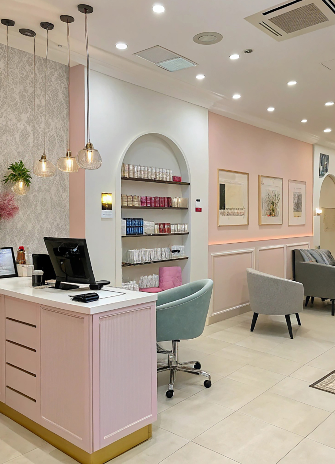 Luxury beauty salon reception area with an elegant desk, comfortable seating, mirrors, and sophisticated lighting.